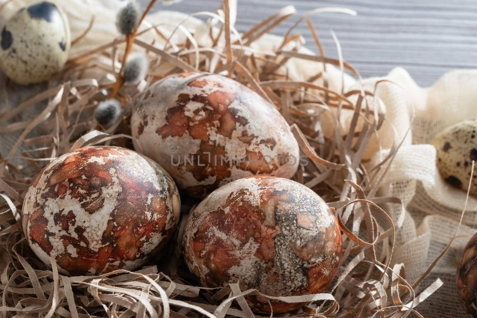 Easter composition - several marble eggs painted with natural dyes in a paper nest on the table.