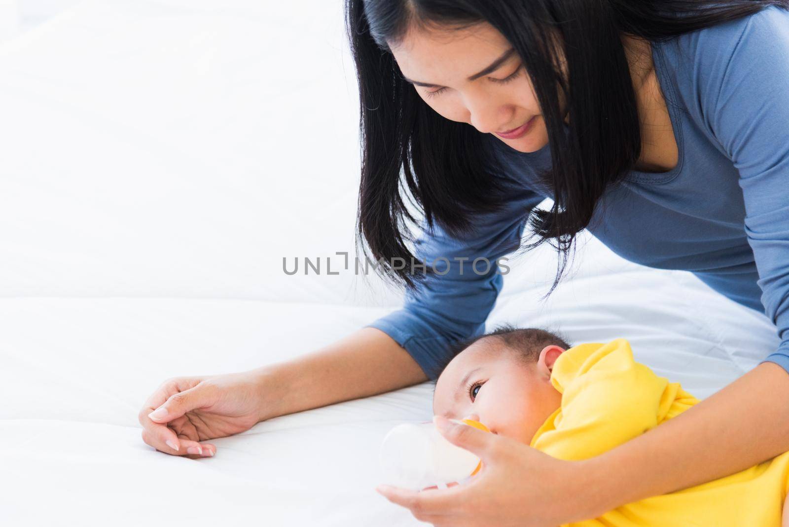 mother holding and feeding infant newborn baby from milk bottle by Sorapop