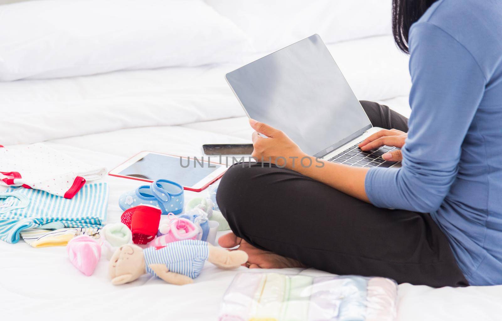 mother shopping online for her baby clothes on laptop computer by Sorapop