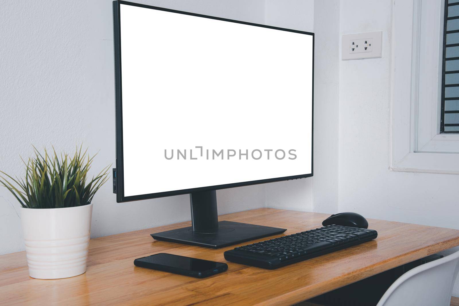 Computer monitor with white blank screen on the business desk with wireless mouse, keyboard at home office over white wall background, Photo of equipment contemporary workspace