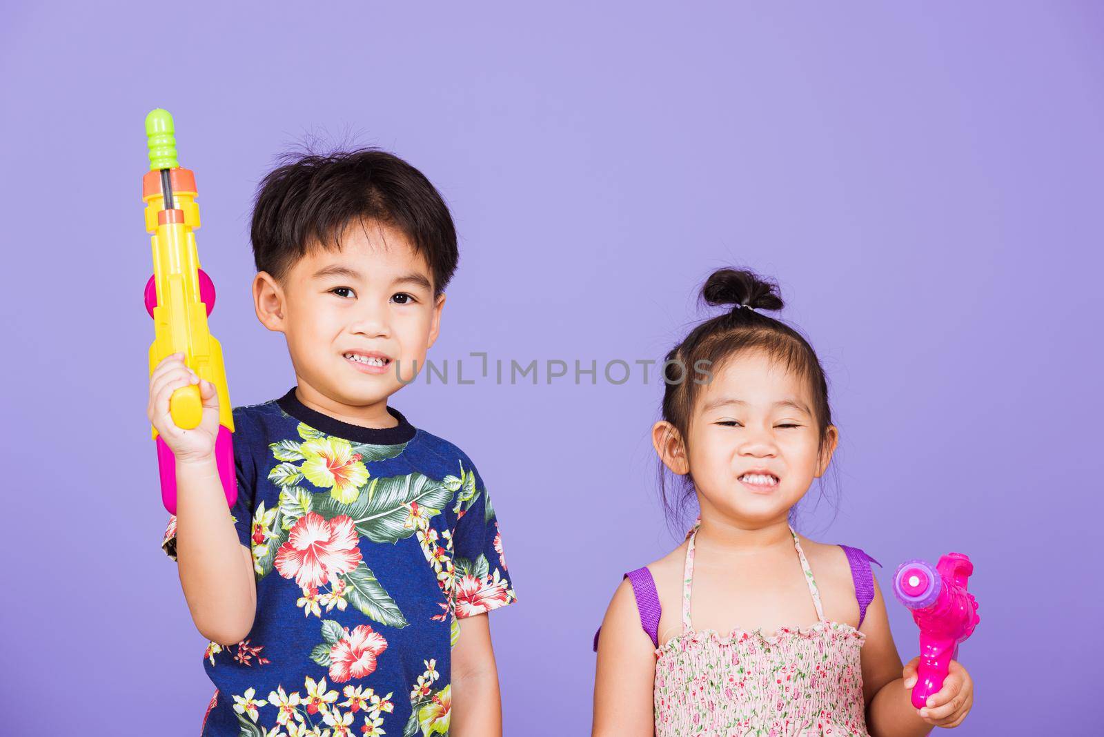 Two Happy Asian little boy and girl holding plastic water gun by Sorapop