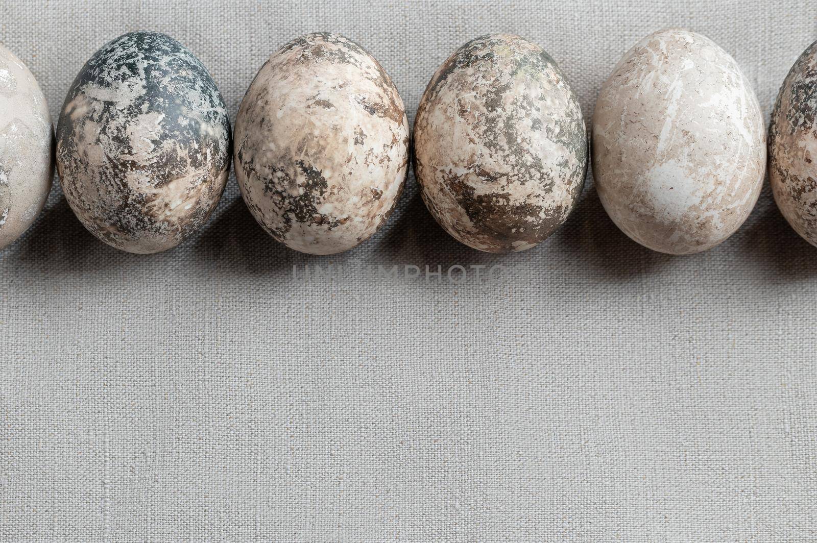 Easter composition - several painted with natural dyes with marble effect on a linen tablecloth in a row.