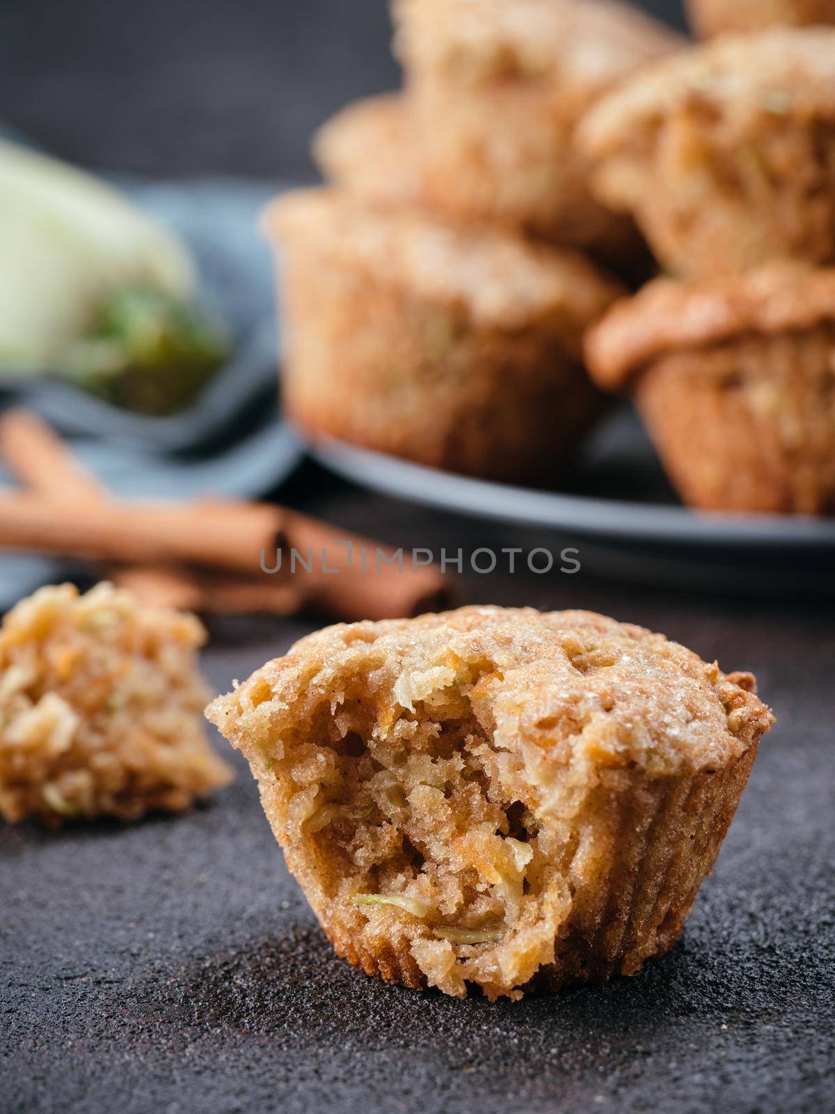 Close up view of muffin with zucchini, carrots, apple and cinnamon on black cement background. Sweet vegetables homemade muffins. Toddler-friendly recipe idea. Copy space. Shallow DOF