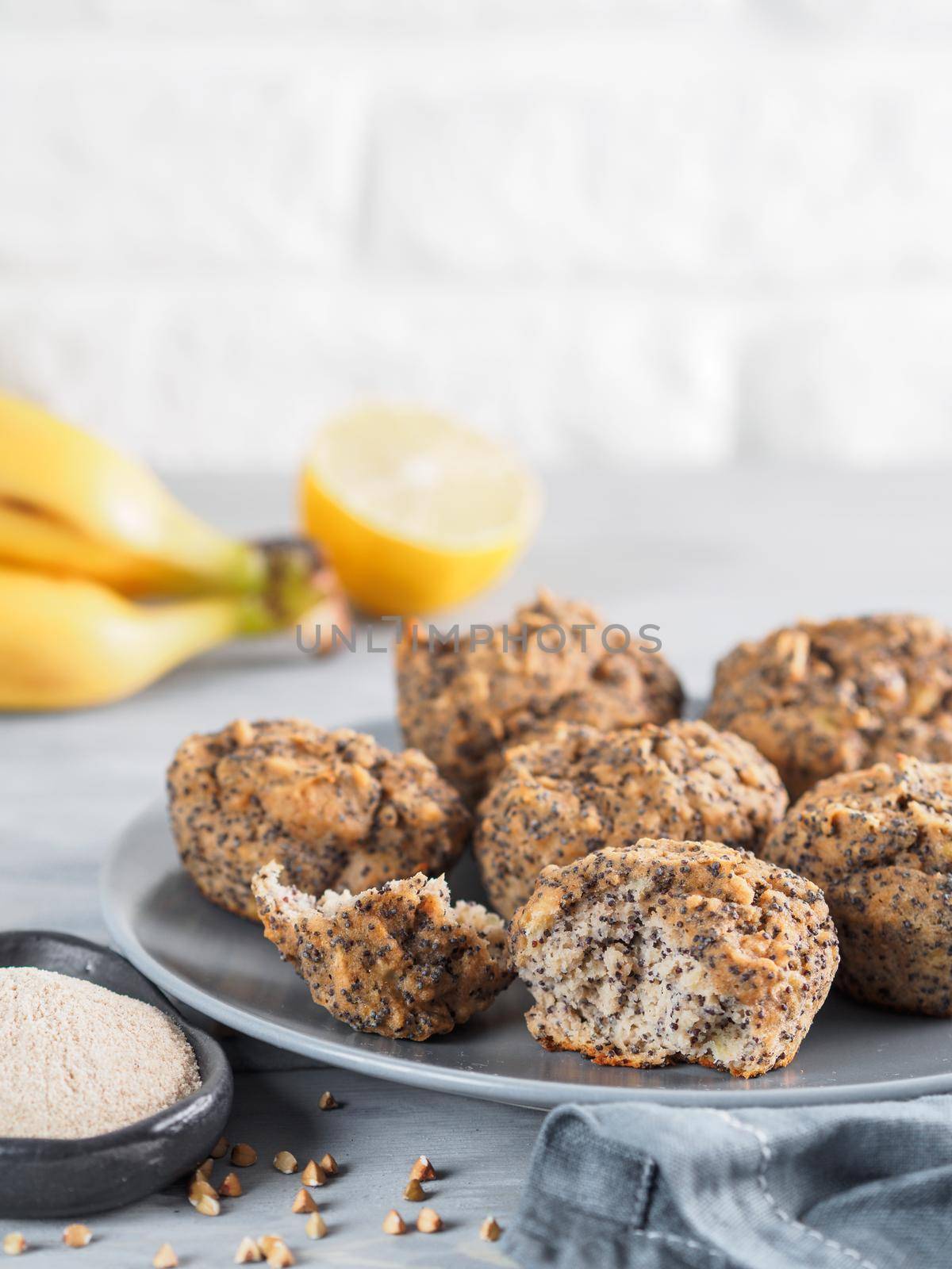 Close-up view of healthy gluten-free homemmade banana muffins with buckwheat flour. Vegan muffins with poppy seeds on gray plate over gray wooden table. Copy space