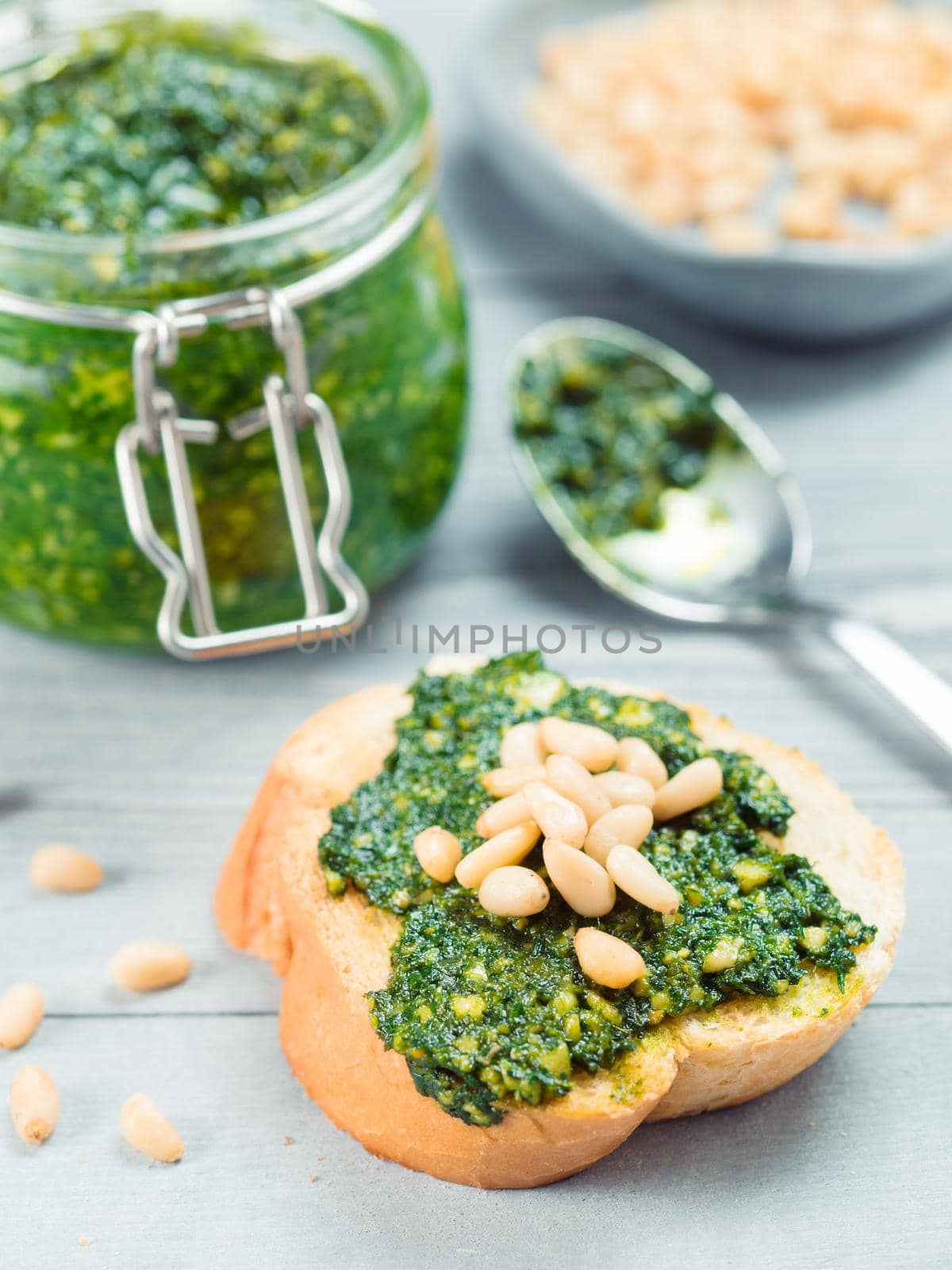 Close up view of baguette bread with fresh basil pesto sauce on gray wooden table. Copy space.