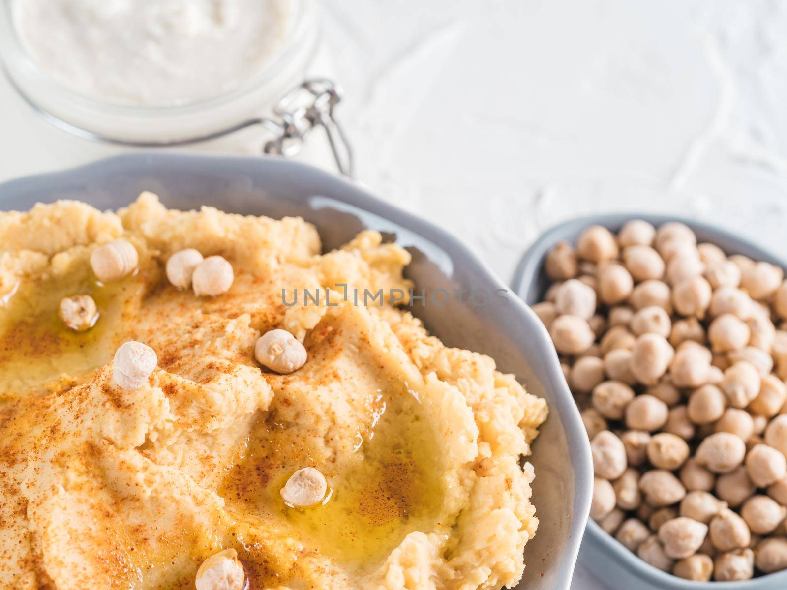 Homemade hummus with olive oil in gray bowl and tahini. Traditional middle eastern homemade appetizer hummus - healthy vegan paste snack. Vegetarian diet and nutrition protein food concept and idea