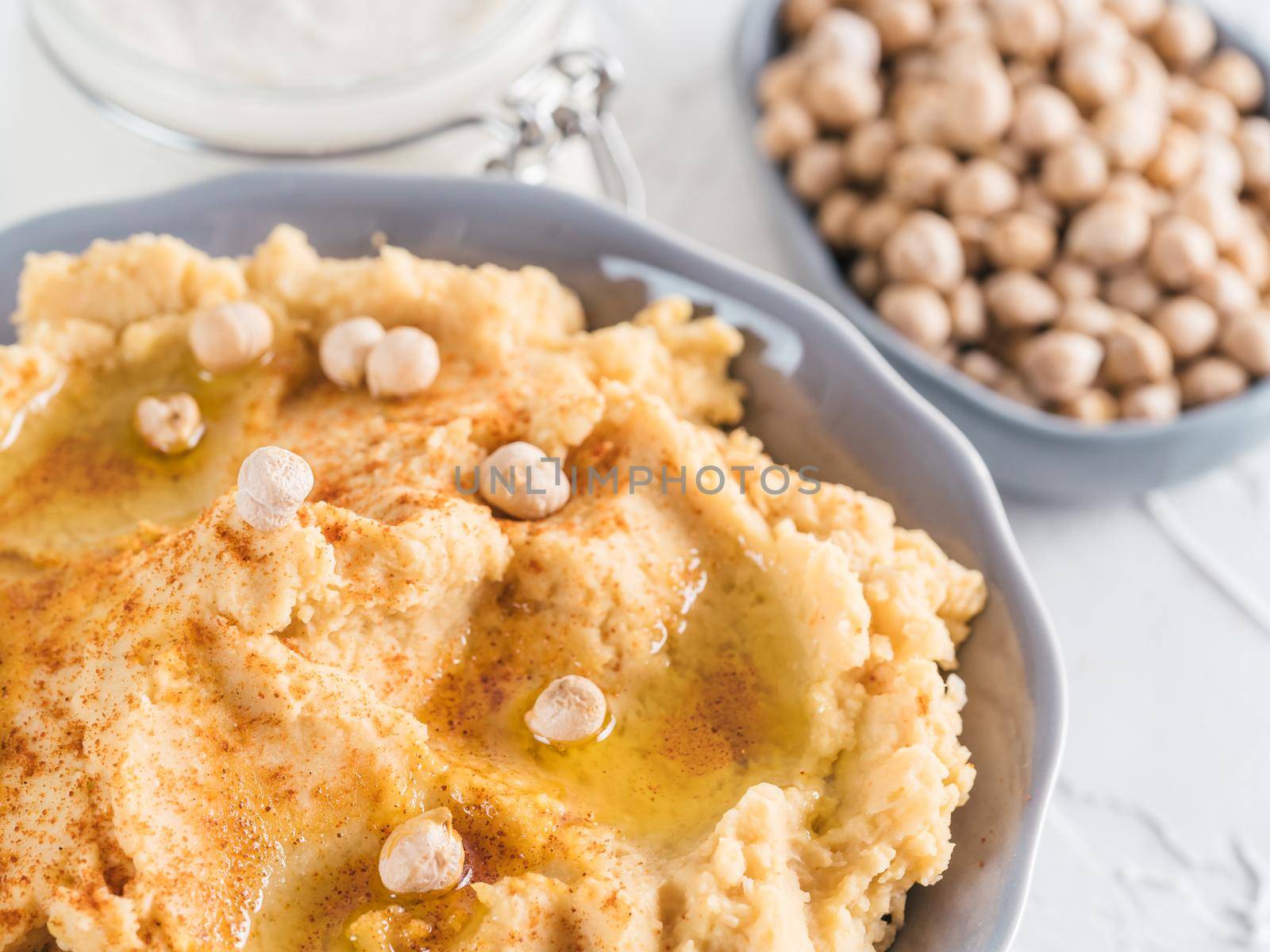 Homemade hummus with olive oil in gray bowl and tahini. Traditional middle eastern homemade appetizer hummus - healthy vegan paste snack. Vegetarian diet and nutrition protein food concept and idea