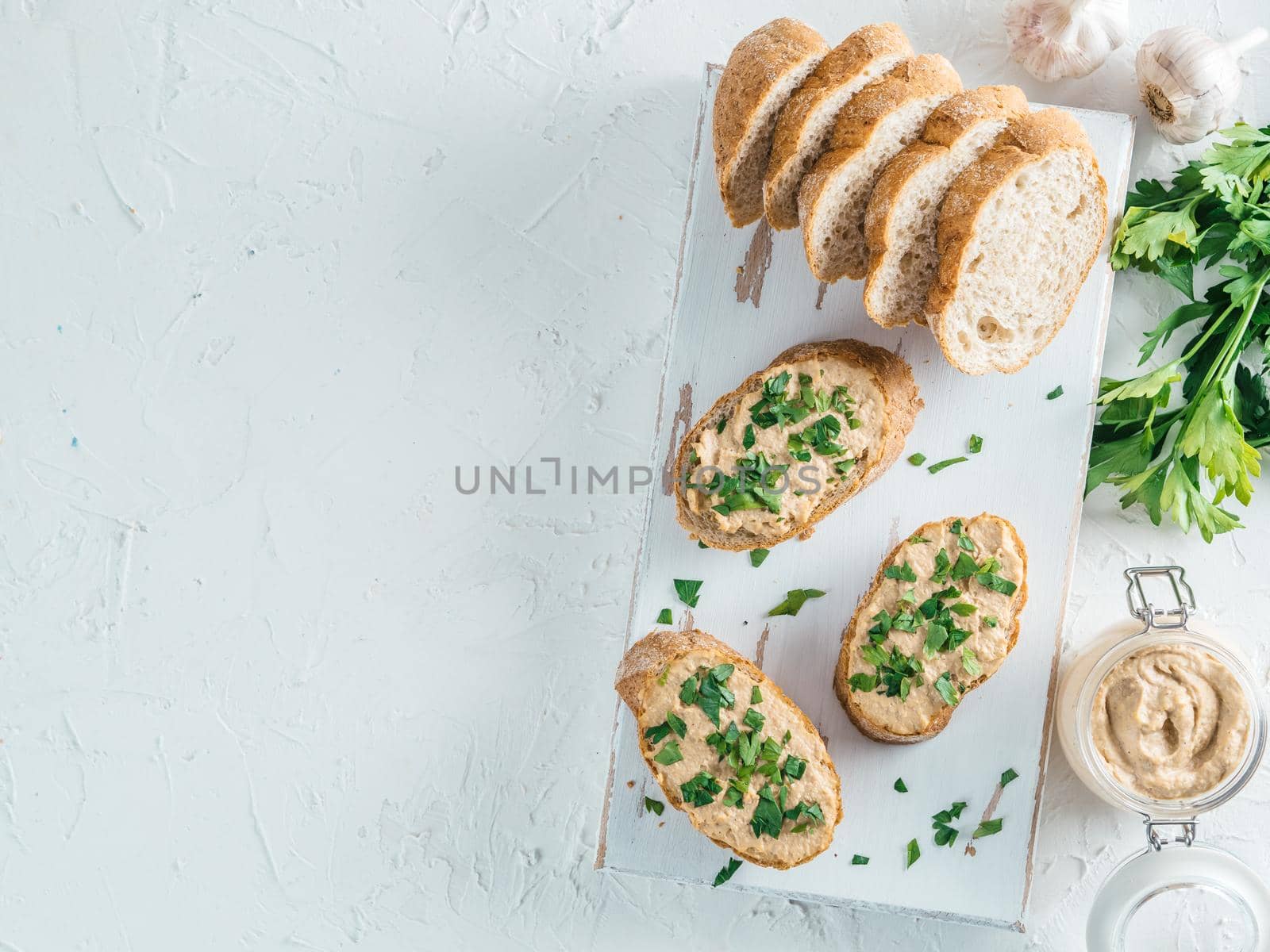 Top view of slice bread with homemade turkey pate and fresh green parsley on white rustic kutting board over white concrete background, Shallow DOF. Selective focus Copy space.