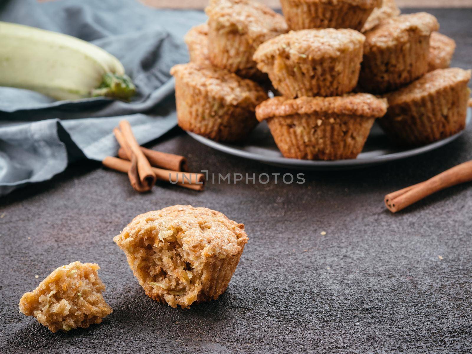 Close up view of muffin with zucchini, carrots, apple and cinnamon on black cement background. Sweet vegetables homemade muffins. Toddler-friendly recipe idea. Copy space. Shallow DOF
