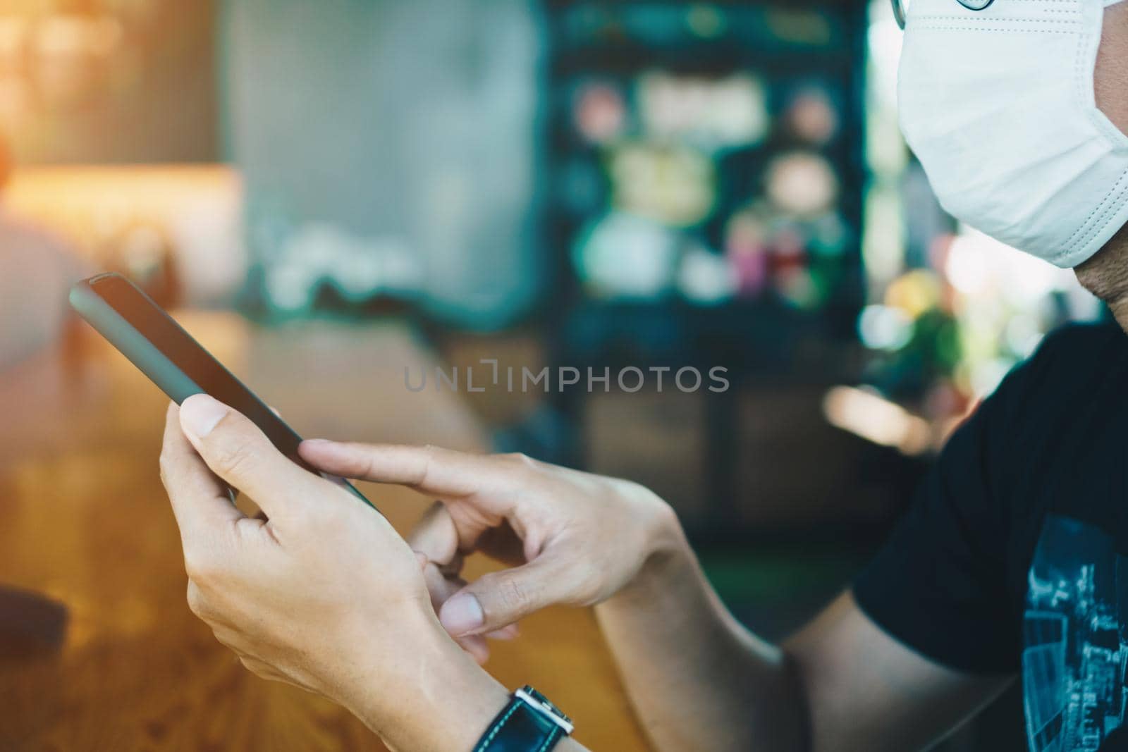 Man wear mask in public area and using smartphone to do work business, social network, communication in public cafe work space area.