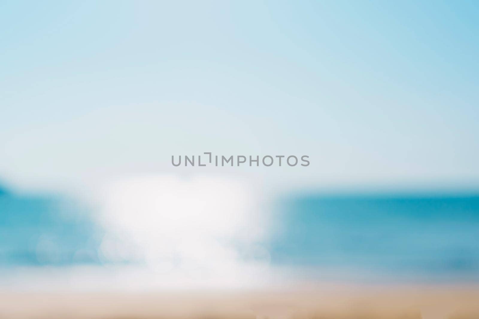 Blur tropical nature clean beach and white sand in summer season with sun light blue sky background.