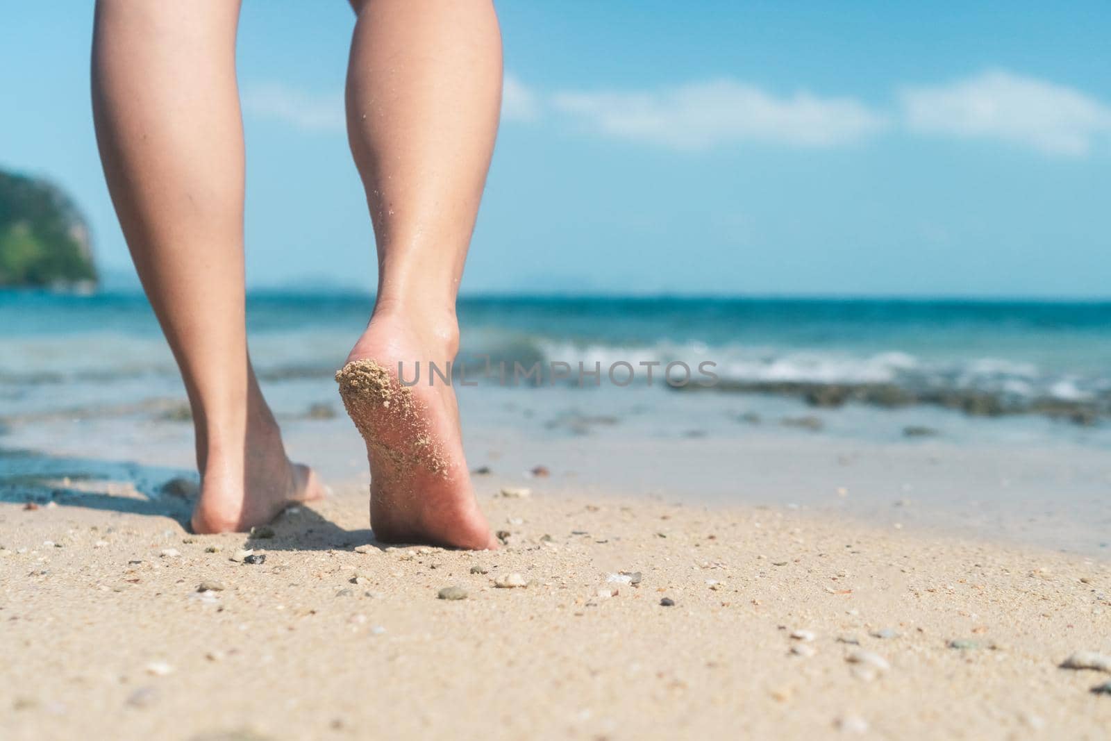 Woman feet walk slow life and relax on sand tropical beach with blue sky background. Vacation and holiday concept.