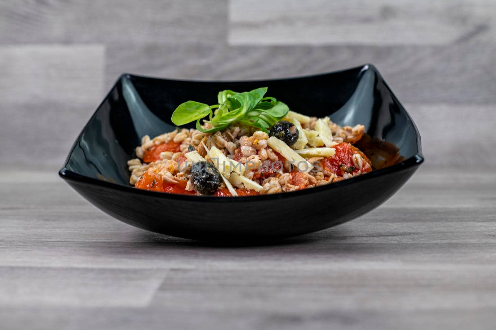 served on black plate of farroset salad on wooden table