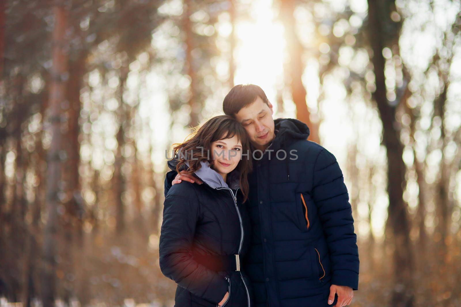 Winter portrait of a young interracial couple as they hug each other by selinsmo
