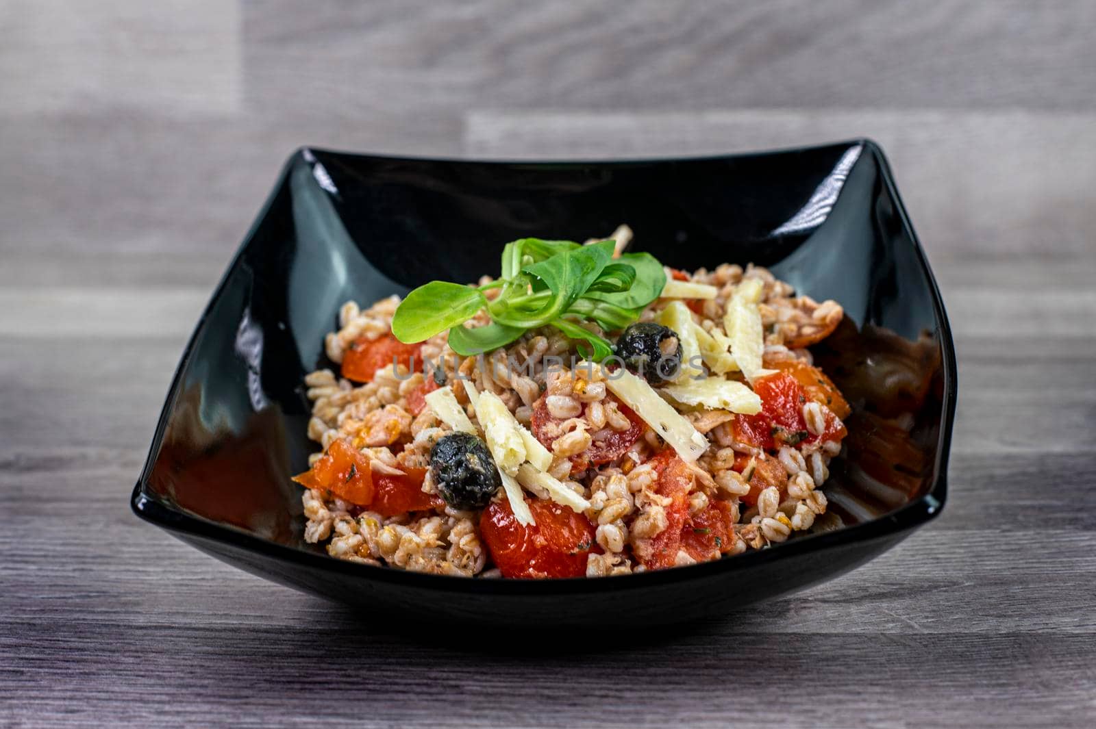 served on black plate of farroset salad on wooden table