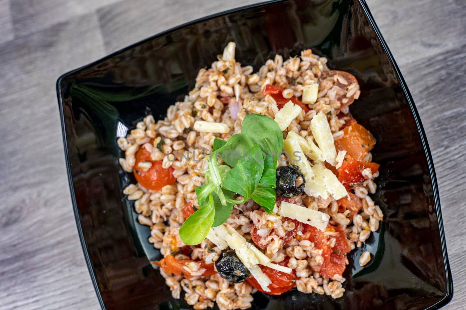 served on black plate of farroset salad on wooden table
