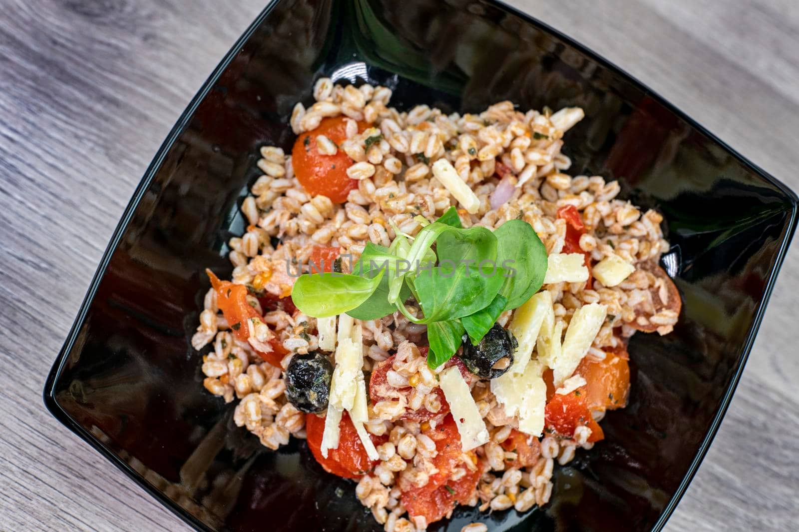 served on black plate of farroset salad on wooden table