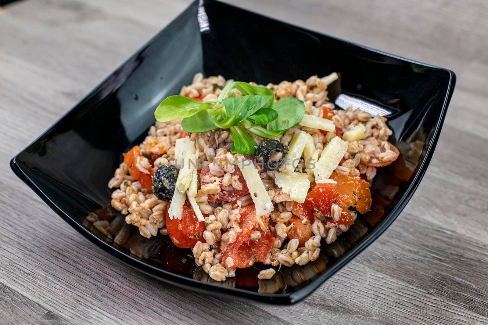 served on black plate of farroset salad on wooden table