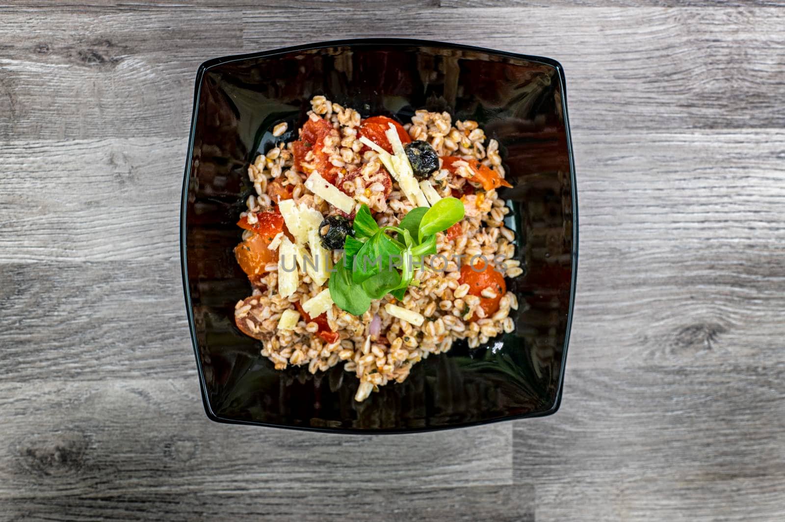 served on black plate of farroset salad on wooden table