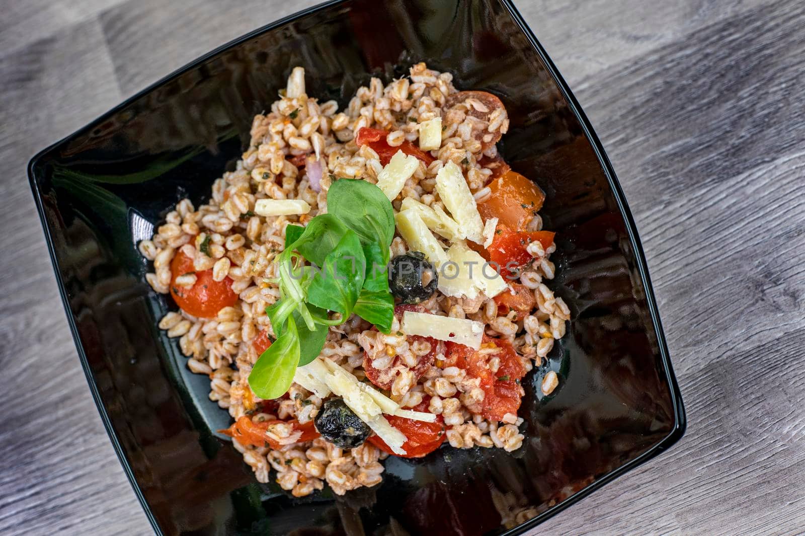 served on black plate of farroset salad on wooden table