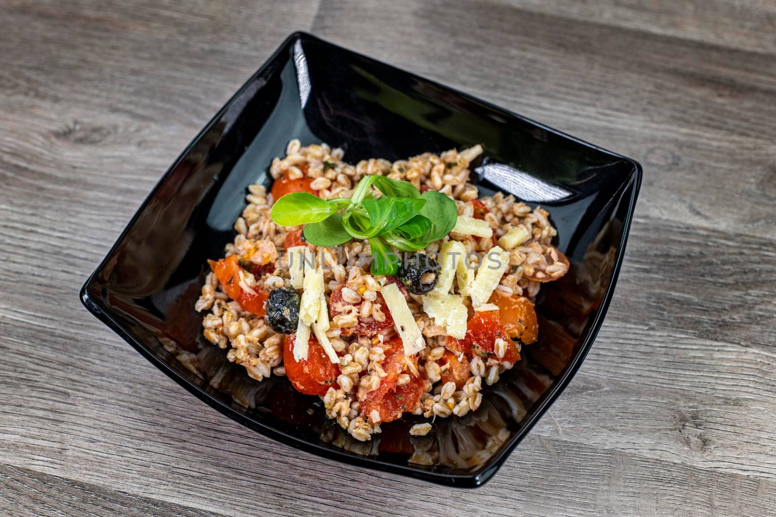 served on black plate of farroset salad on wooden table