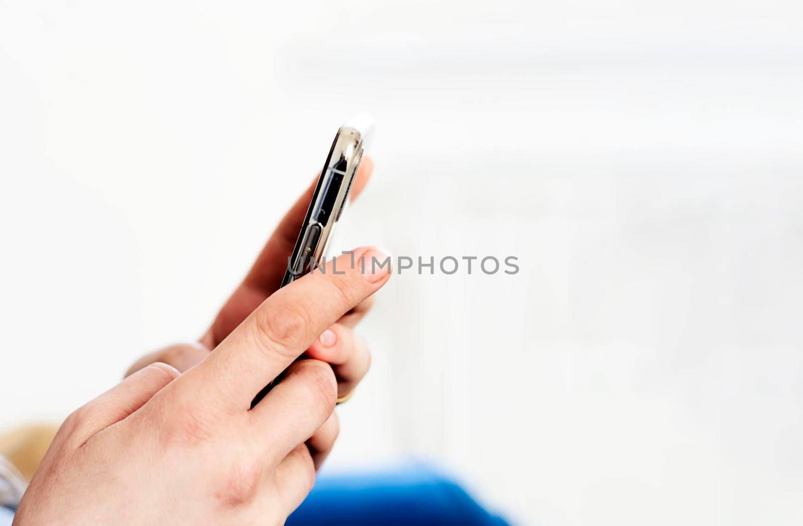the hands of a young caucasian brunette woman while holding a smartphone typing on the touch screen. Technology and mobile connection.
