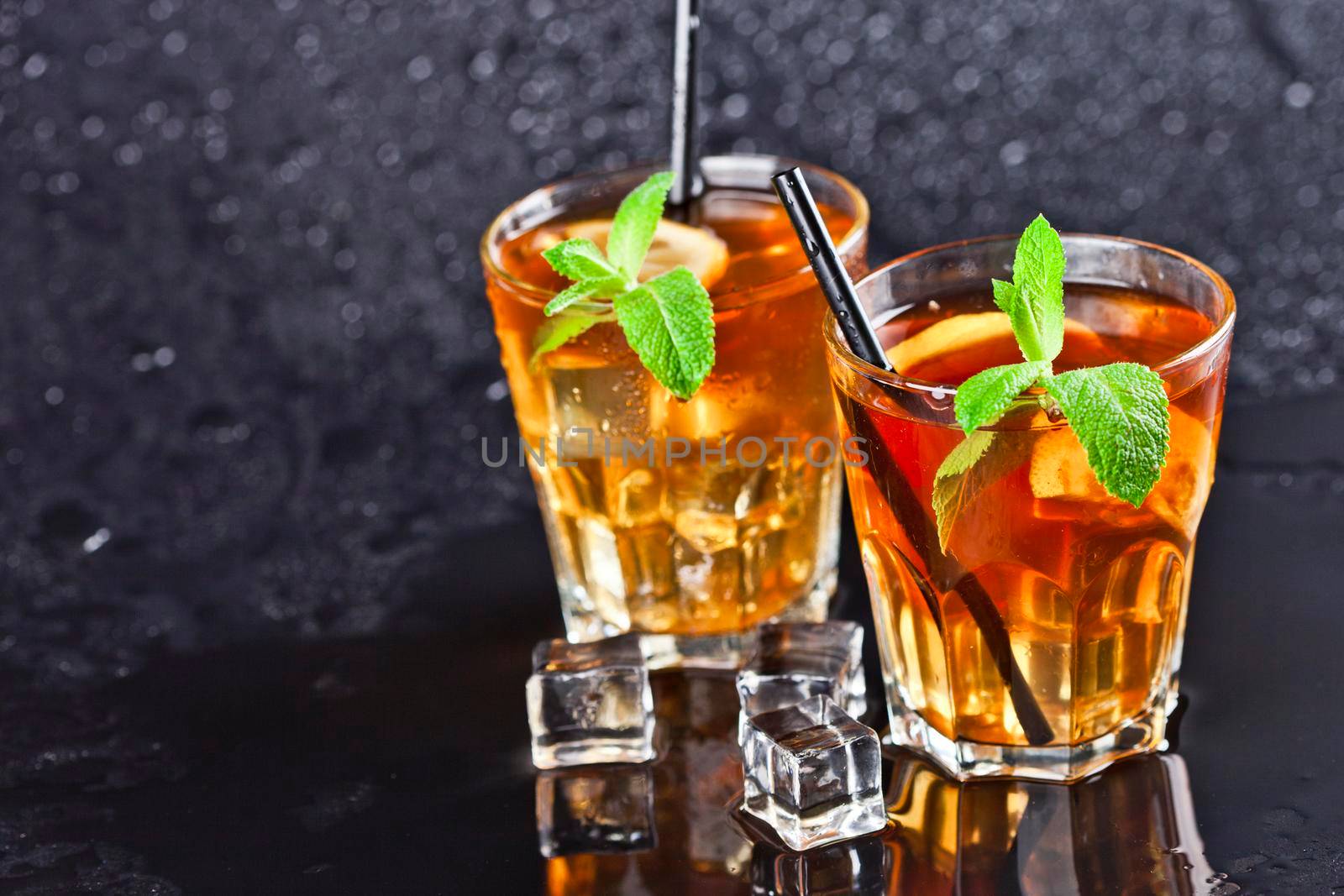 Two glasses with cold traditional iced tea with lemon, mint leaves and ice cubes. by marylooo