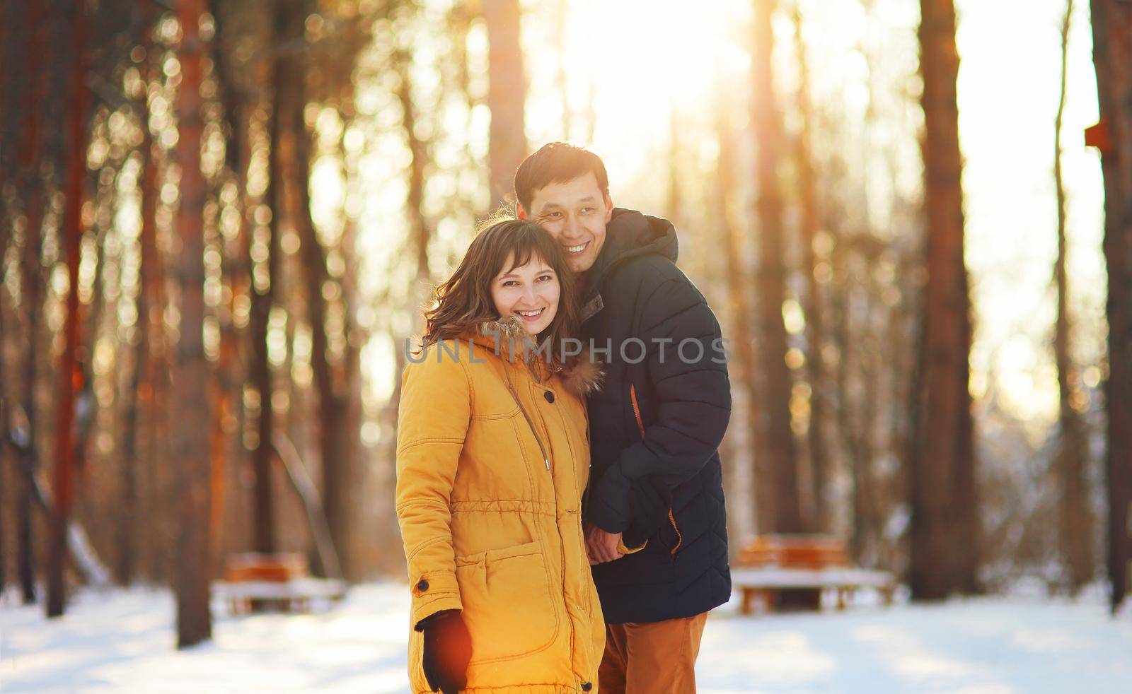 Warm winter portrait of young interracial smiling couple on a walk in the forest.