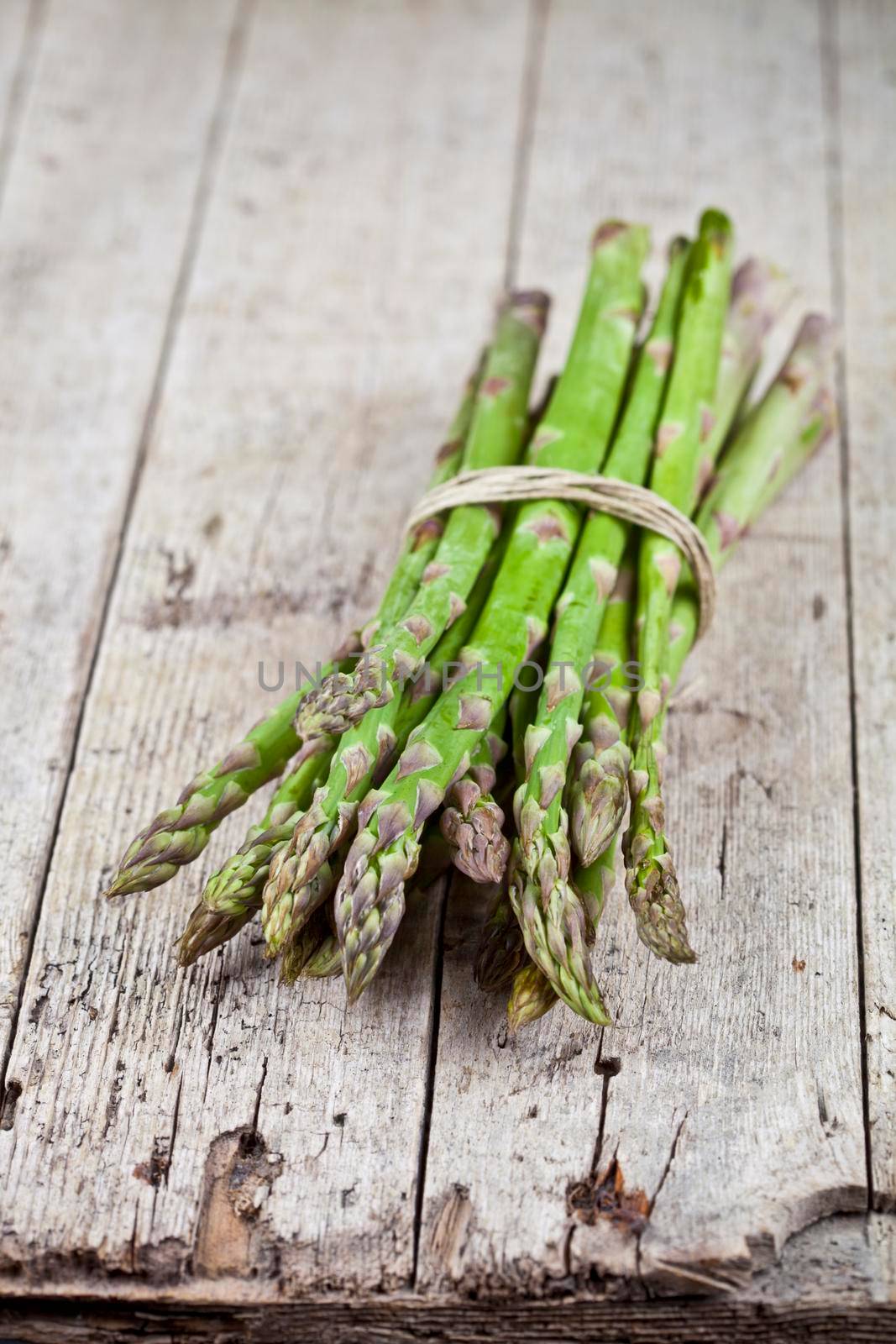 Bunch of fresh raw garden asparagus on rustic wooden table background. Green spring vegetables. by marylooo