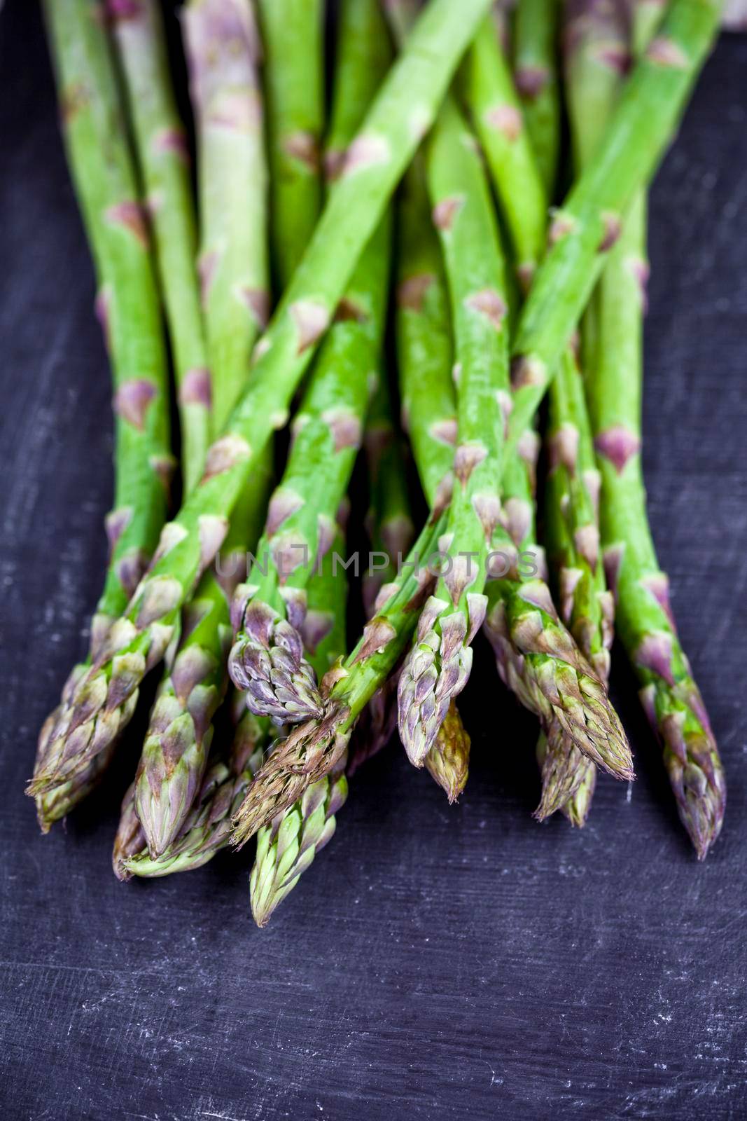 Organic fresh raw garden asparagus closeup on black board background. Green spring vegetables. by marylooo