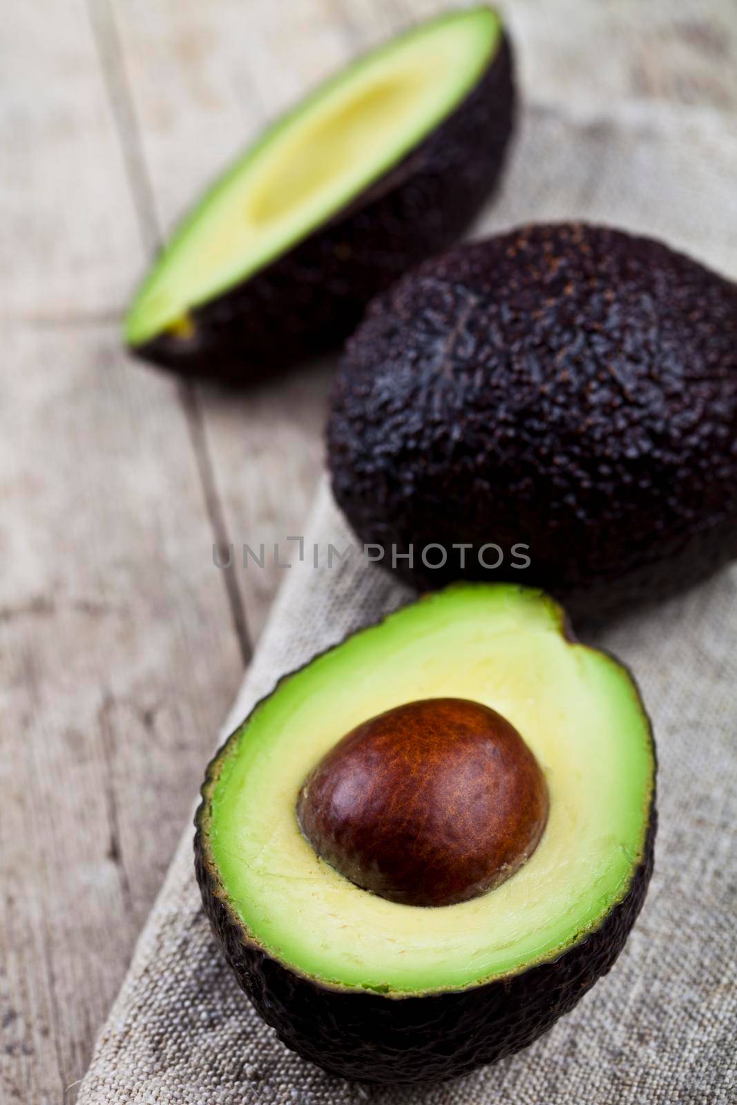 Organic avocado on linen napkin on rustic wooden table background. by marylooo