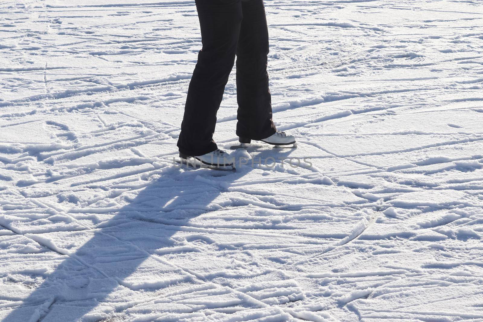 Close up on womans feet wearing ice skating boots and standing on ice