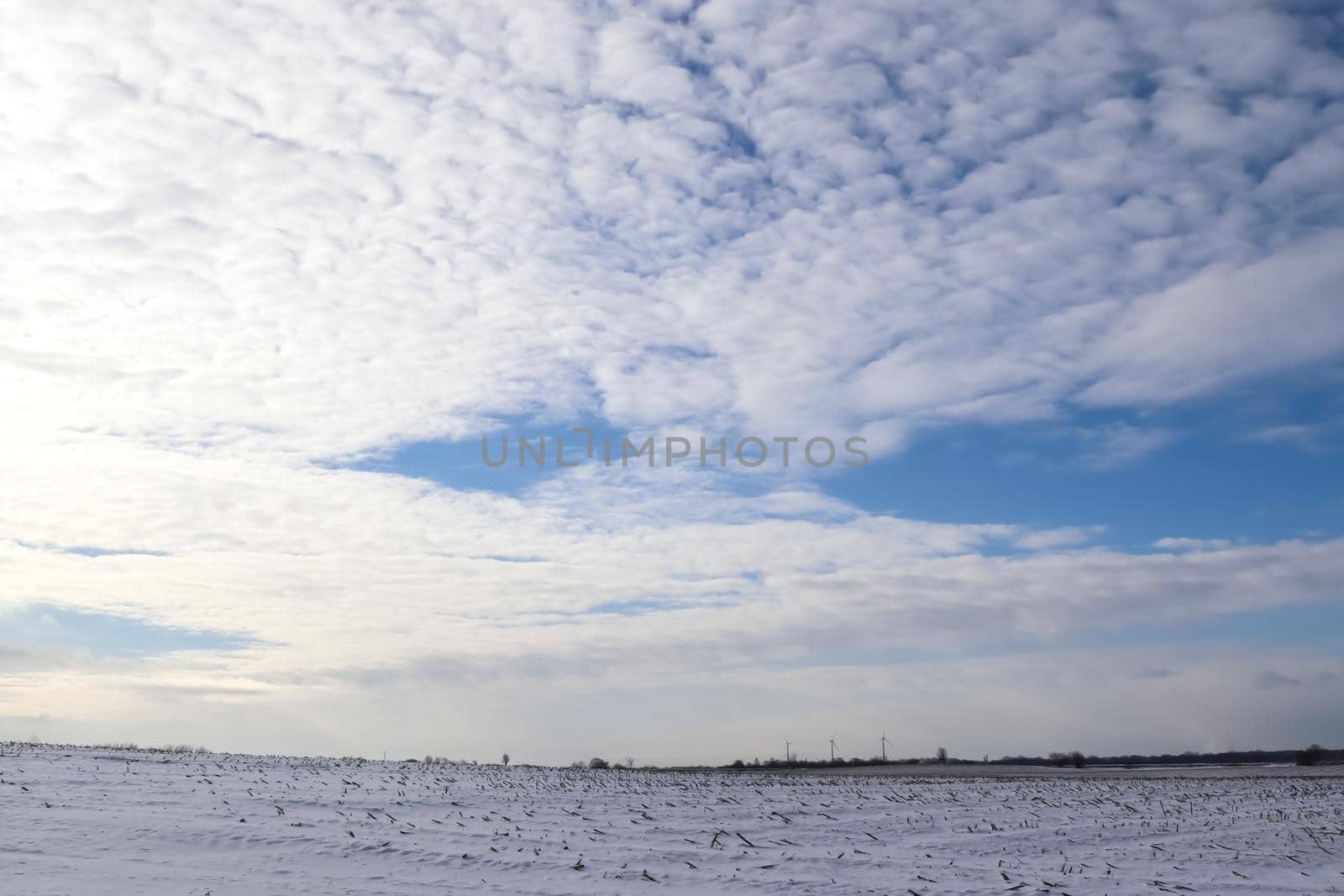 Beautiful clouds in the sky looking over a snow covered agricultural field