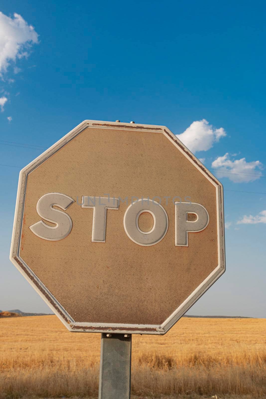 Old stop sign faded by the sun on a road in southern Spain