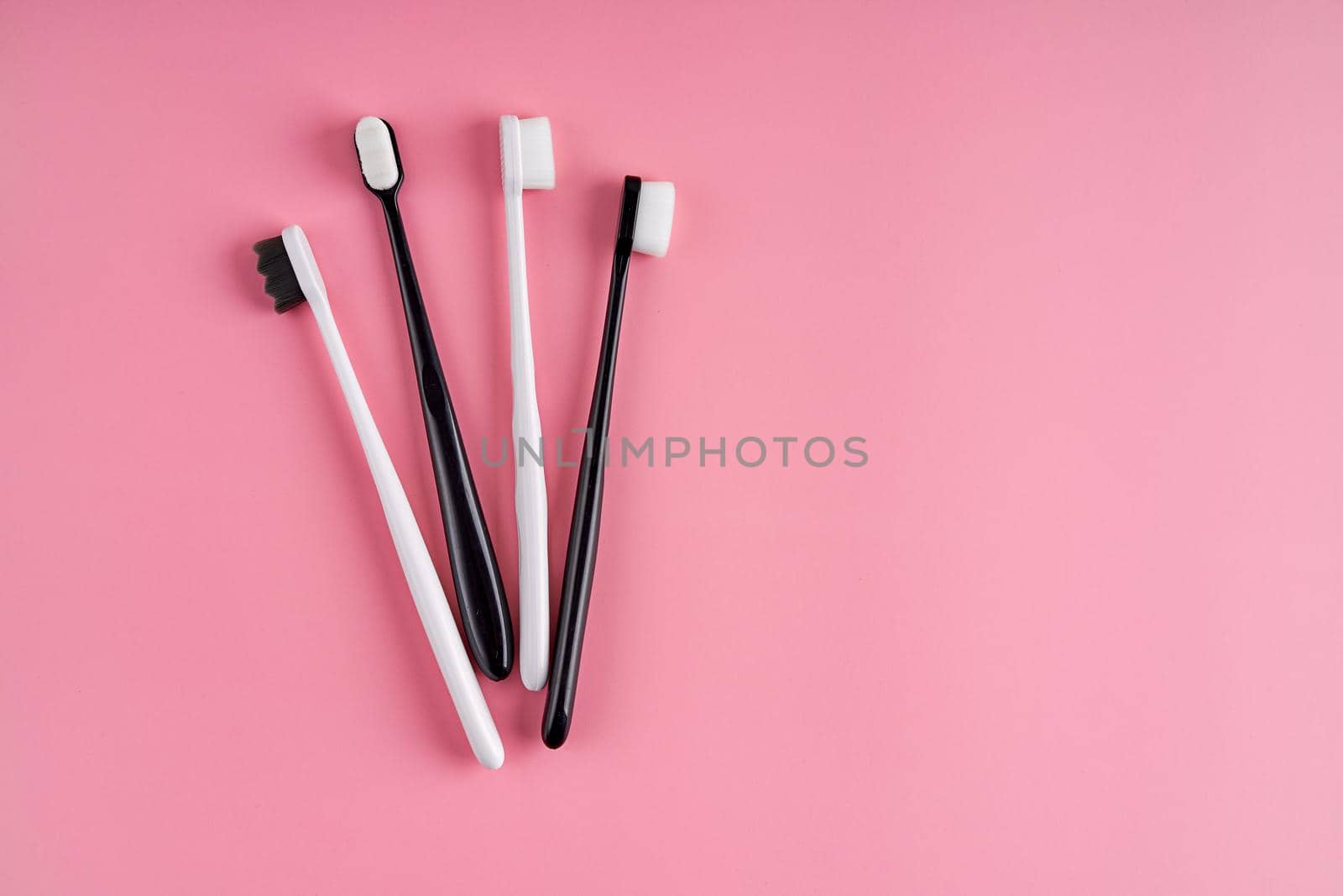 Fashionable toothbrush with soft bristles. Popular toothbrushes. Hygiene trends. Kit of toothbrushes on pink background.