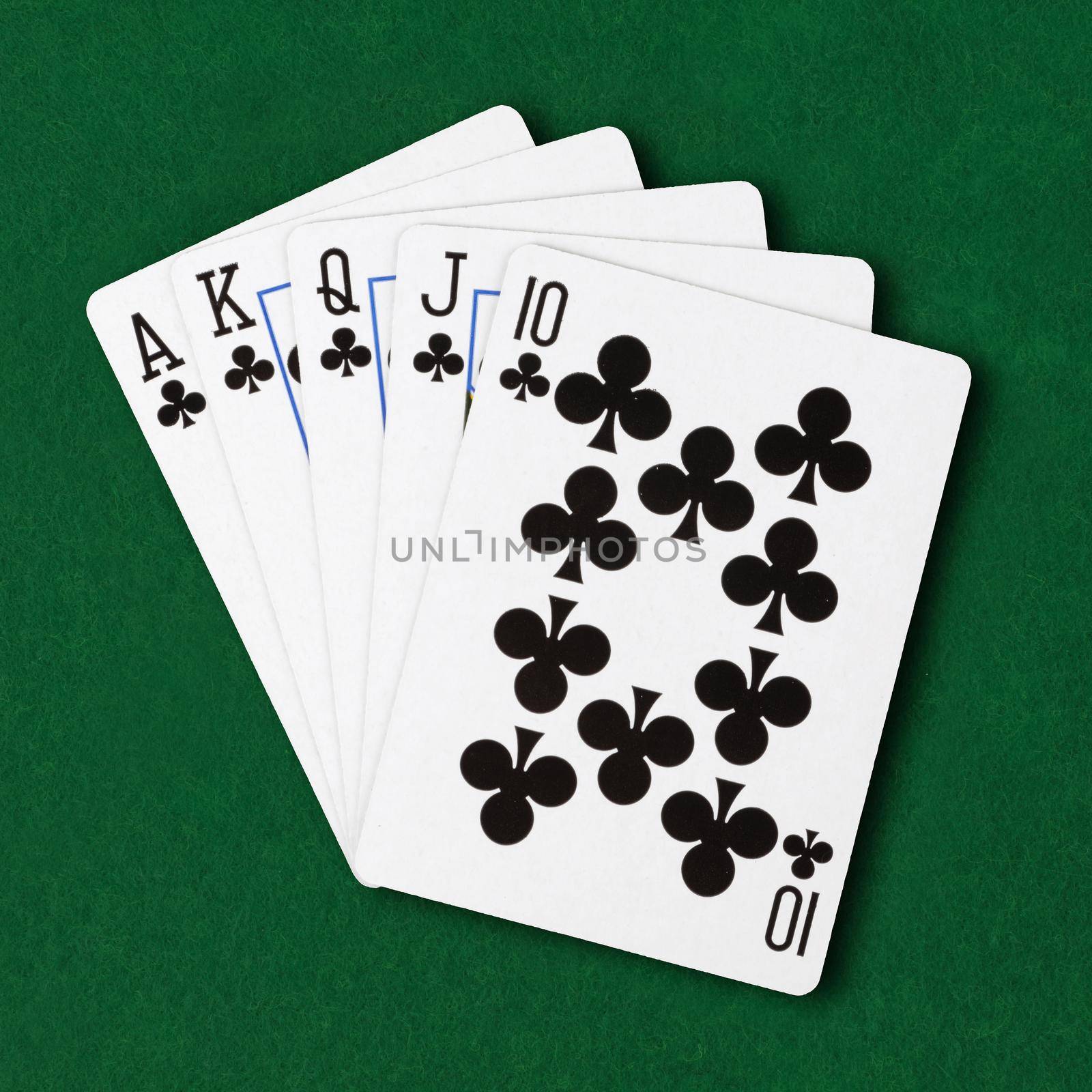 A hand of cards clubs royal flush on green card table cloth winning hand business concept