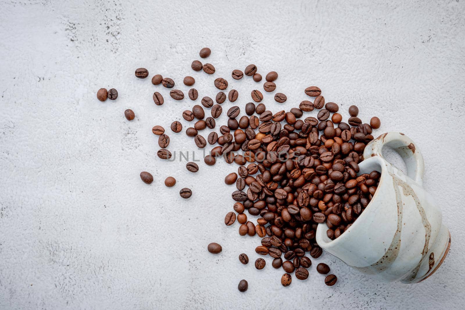 Roasted coffee beans with scoops setup on white concrete background.