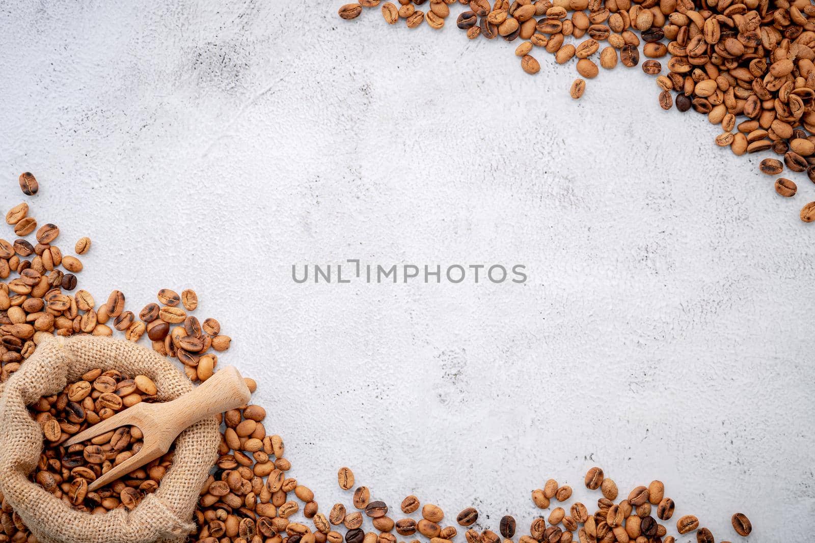 Roasted coffee beans with scoops setup on white concrete background. by kerdkanno