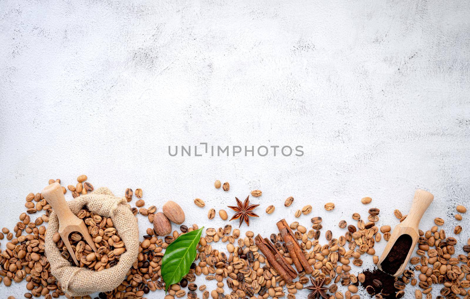 Roasted coffee beans with scoops setup on white concrete background.