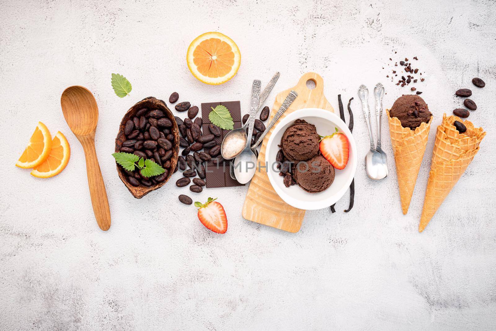 Chocolate ice cream flavours in bowl with dark chocolate and cacao nibs setup on white stone background .