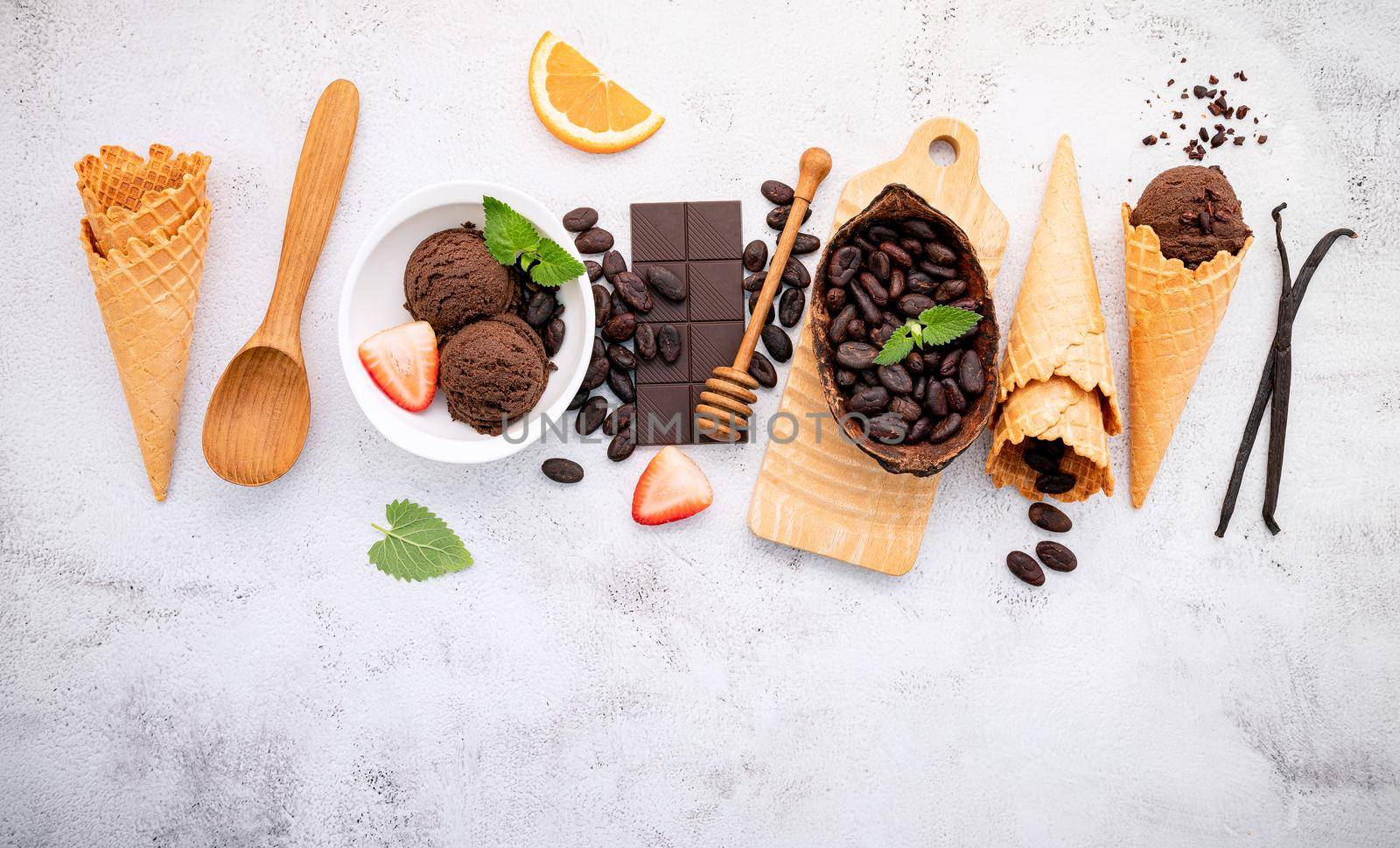 Chocolate ice cream flavours in bowl with dark chocolate and cacao nibs setup on white stone background .