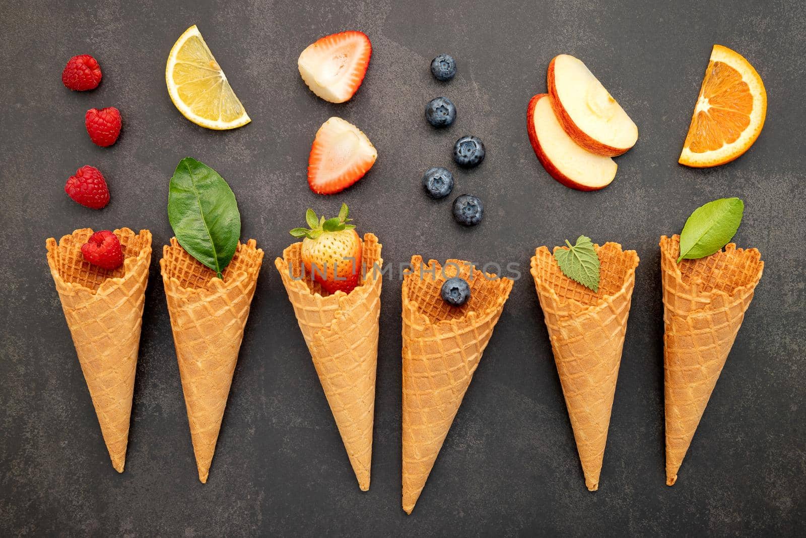 Various of fruits  in cones blueberry ,strawberry ,raspberries and orange setup on white stone background.  Summer and Sweet menu concept.