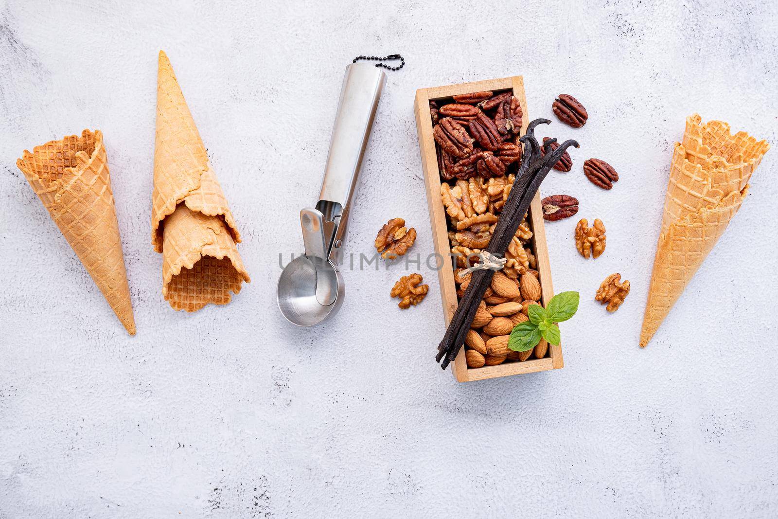 Empty  ice cream cones  with mixed nut setup on white stone background . Summer and Sweet menu concept.