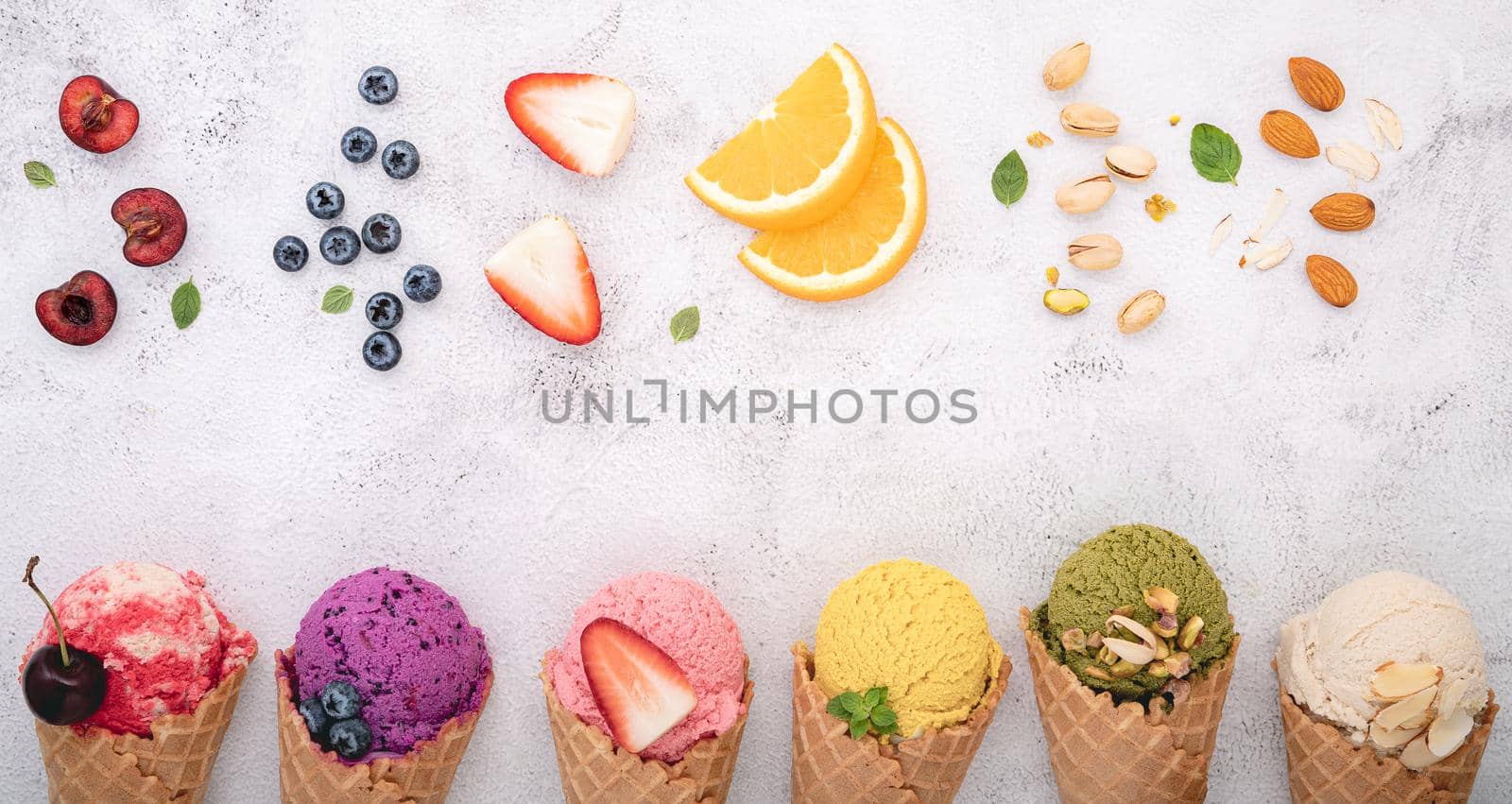 Various of ice cream flavor in cones blueberry ,pistachio ,almond ,orange and cherry setup on white stone background . Summer and Sweet menu concept.