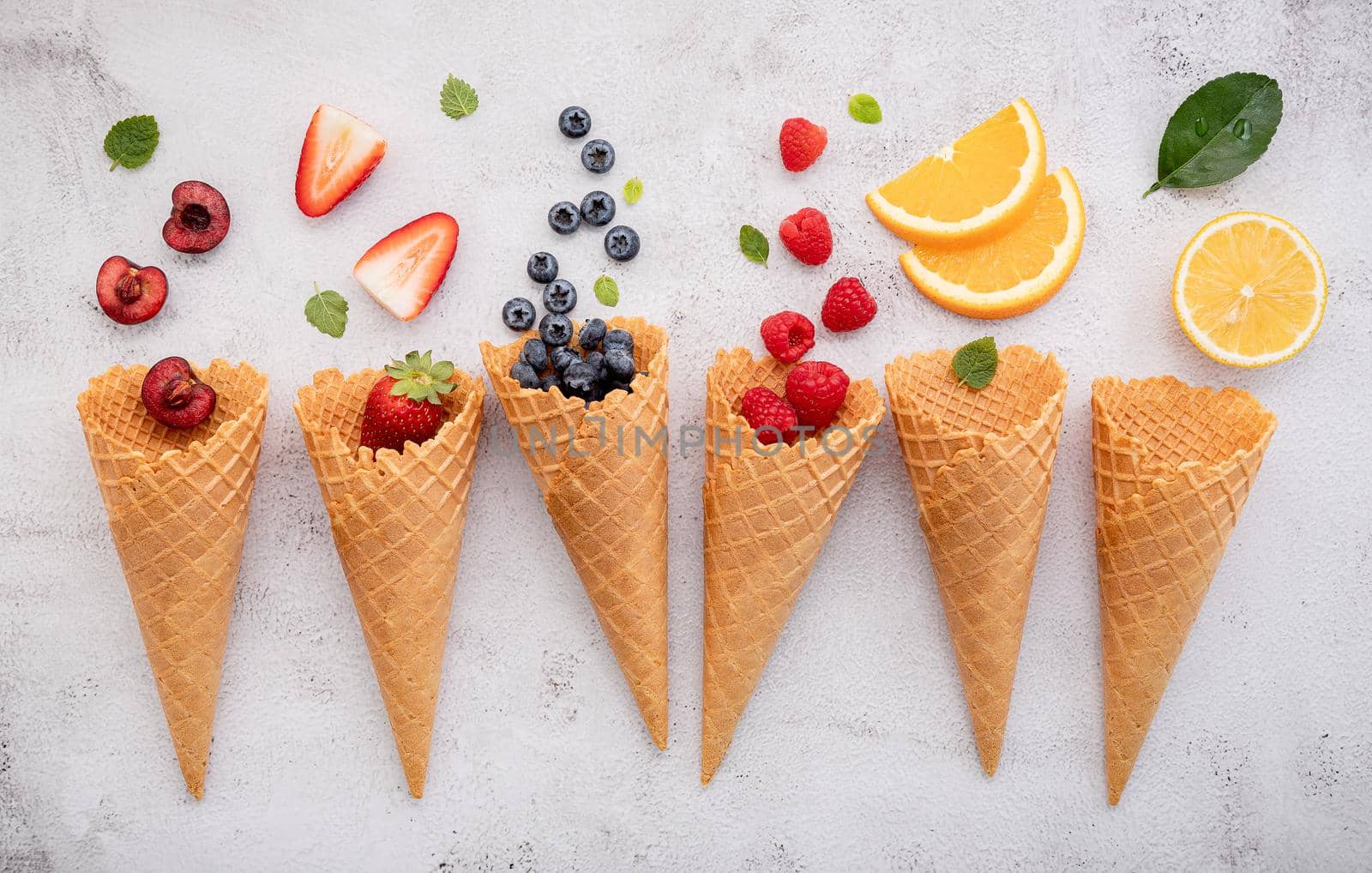 Various of fruits  in cones blueberry ,strawberry ,raspberries and strawberry setup on white stone background . Summer and Sweet menu concept.