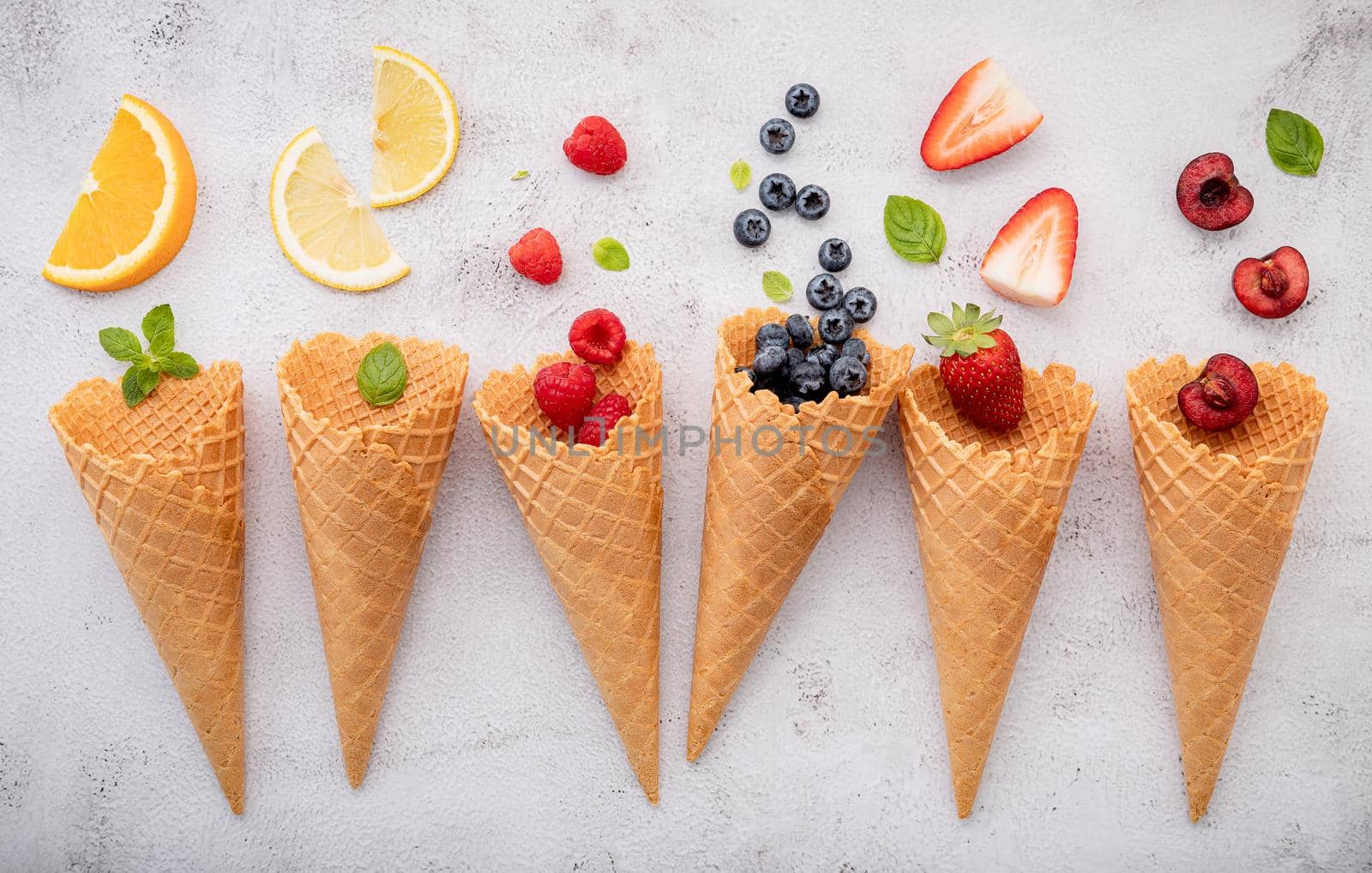 Various of fruits  in cones blueberry ,strawberry ,raspberries and strawberry setup on white stone background . Summer and Sweet menu concept.