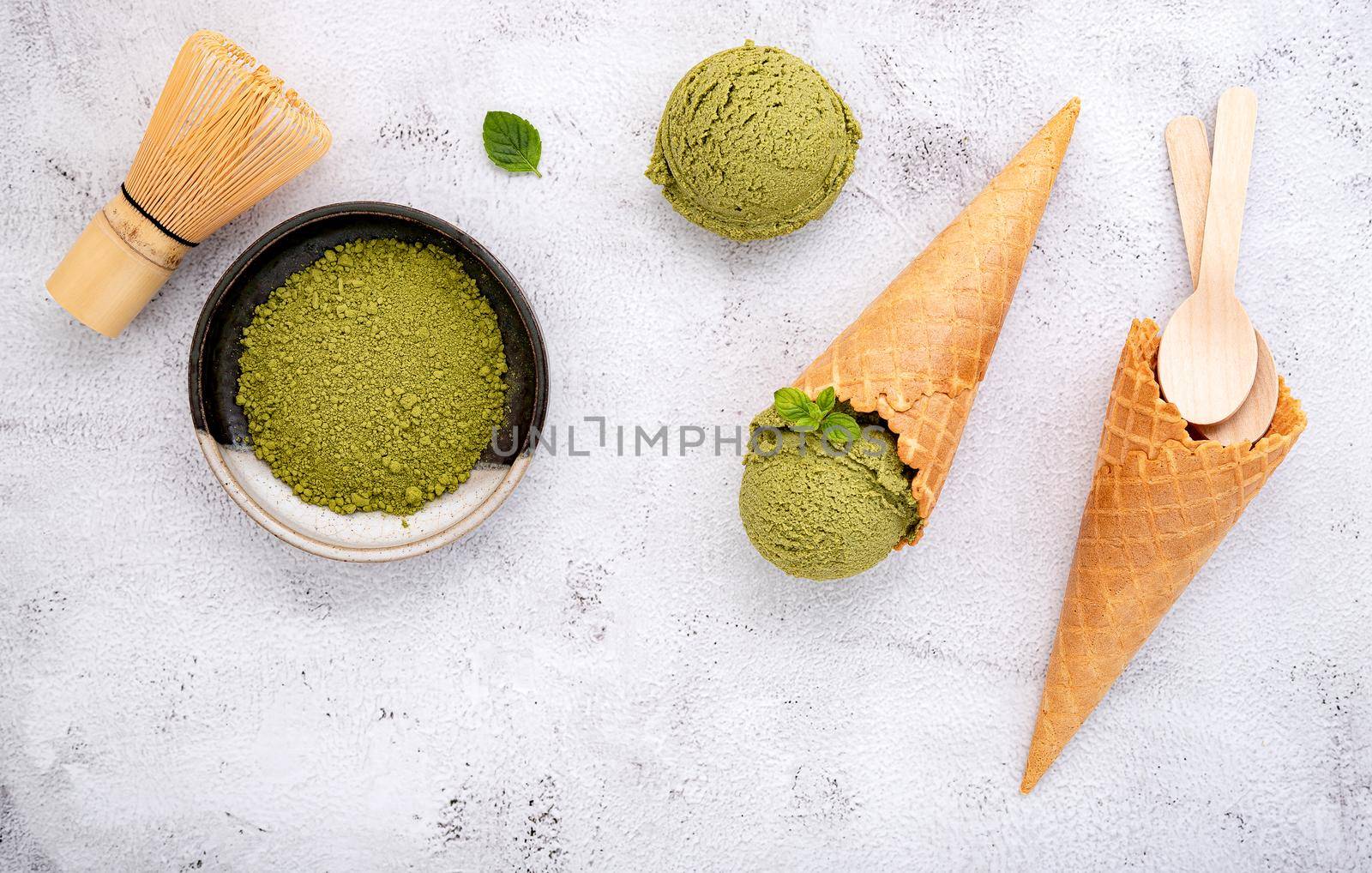 Matcha green tea ice cream with waffle cone and mint leaves  setup on white stone background . Summer and Sweet menu concept.