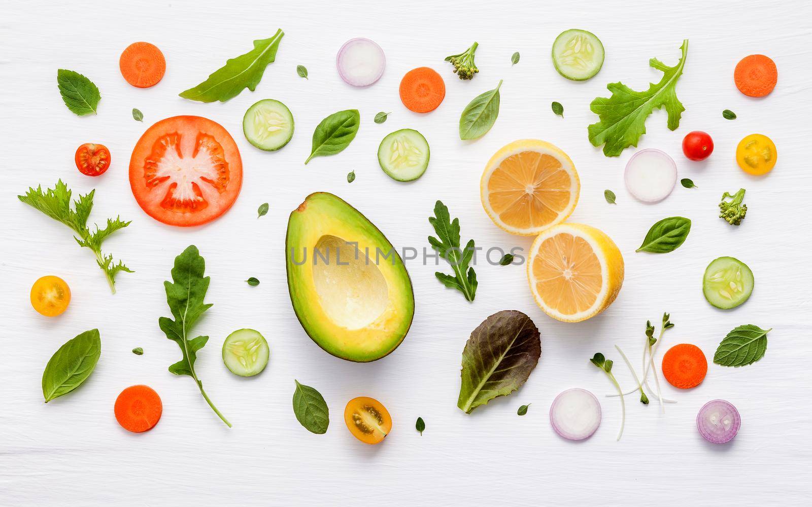 Food pattern with raw ingredients of salad, lettuce leaves, cucumbers, tomatoes, carrots, broccoli, basil ,onion and lemon flat lay on white wooden background.