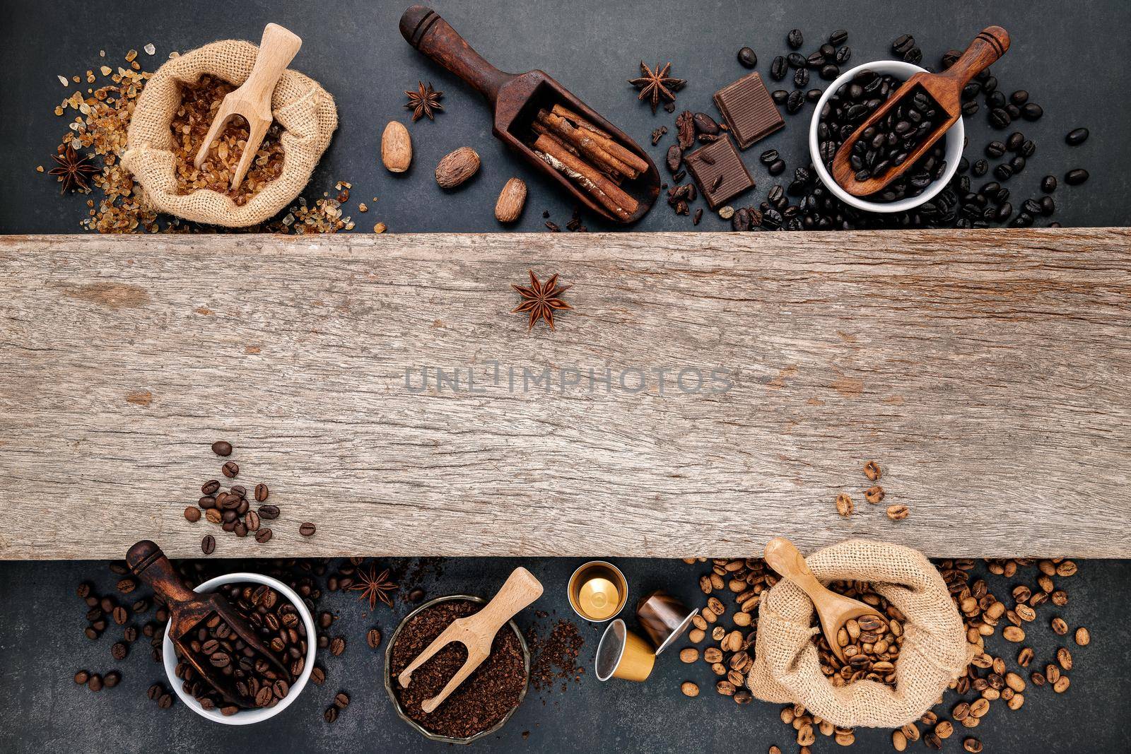 Coffee background with various of roasted coffee beans and flavourful ingredients for make tasty coffee setup on dark stone background.