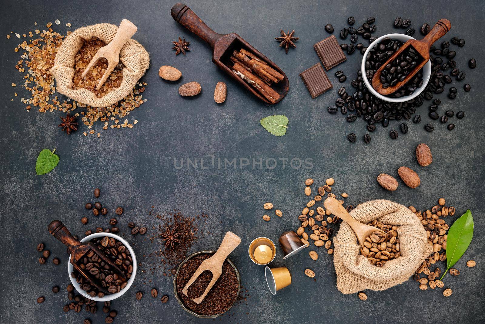 Coffee background with various of roasted coffee beans and flavourful ingredients for make tasty coffee setup on dark stone background. by kerdkanno
